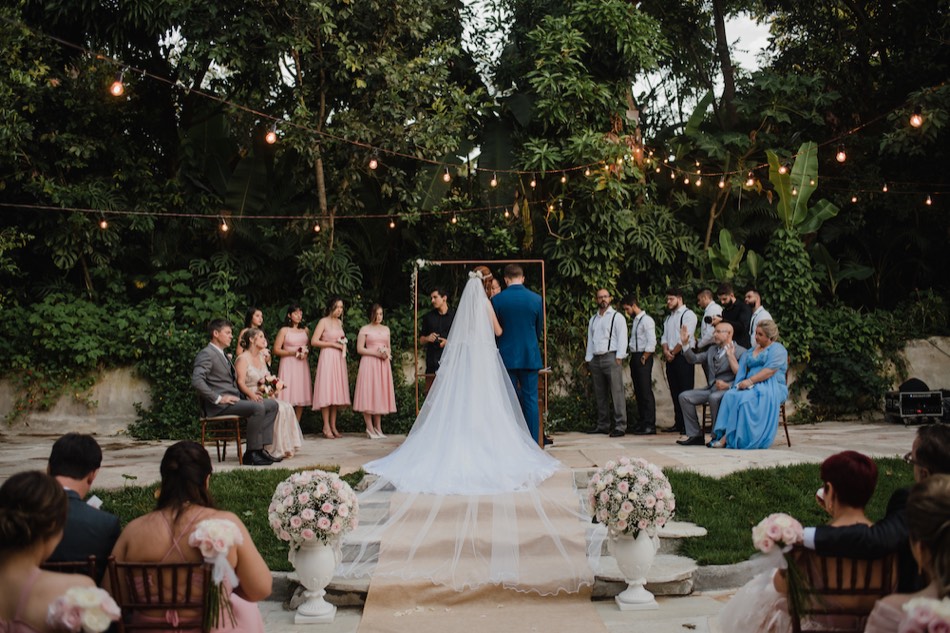 Cerimônia de casamento com madrinhas e padrinhos sob varal de luzes
