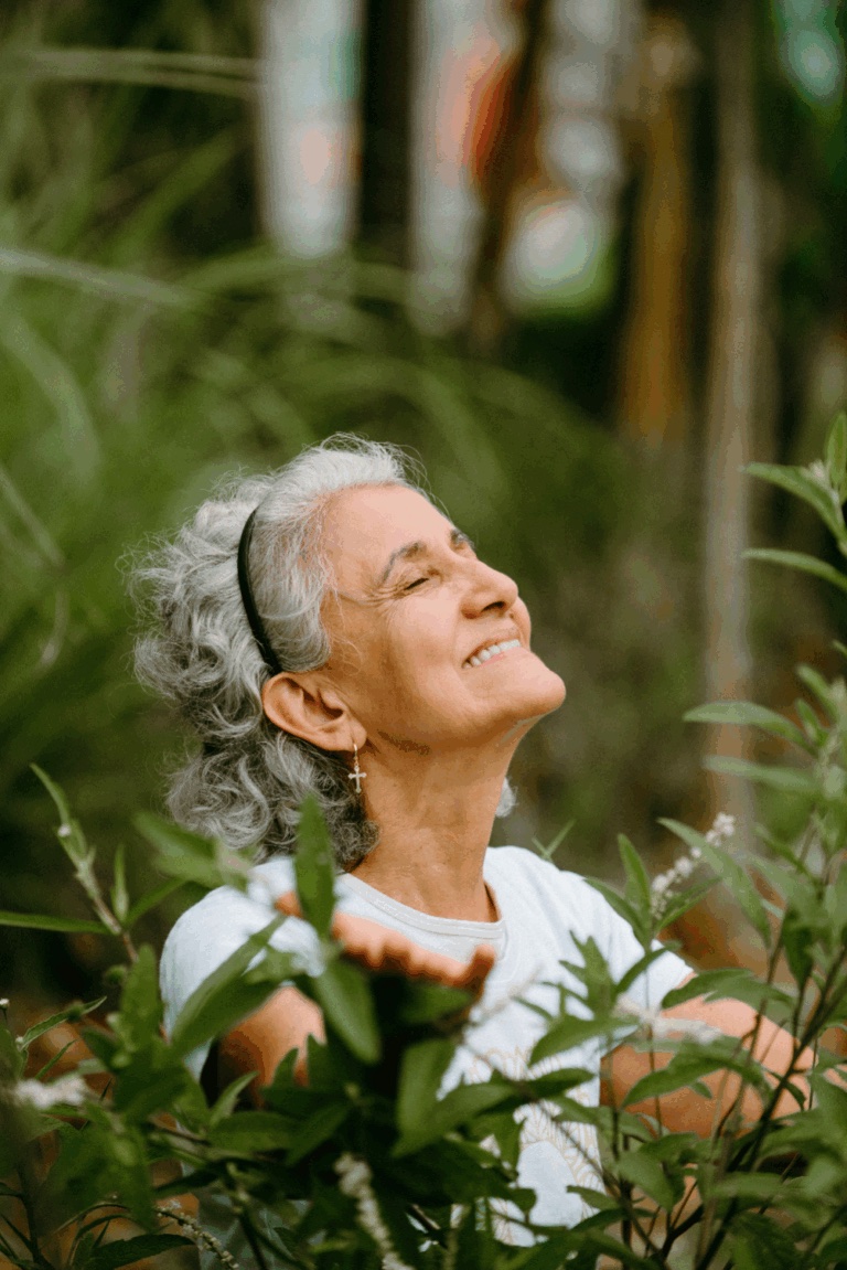 Maria Abadia, fundadora do Sítio Geranium, sorrindo em meio à vegetação